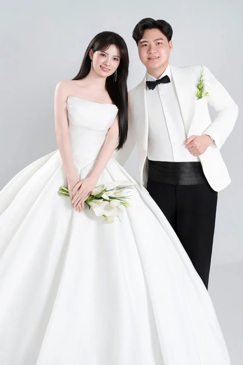 Cô dâu váy trắng và chú rể vest trắng chụp trong studio
